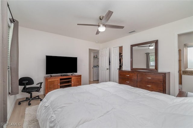 bedroom featuring ceiling fan, washer / dryer, light wood-type flooring, and ensuite bath