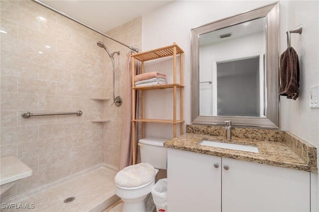 bathroom featuring vanity, toilet, and a tile shower