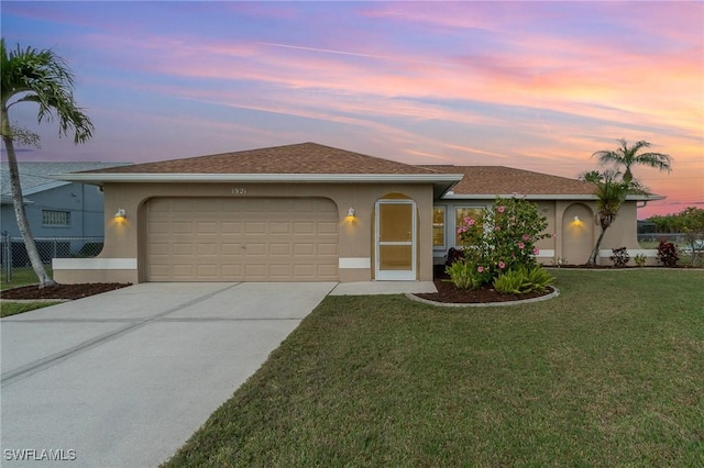 ranch-style home featuring a garage and a lawn