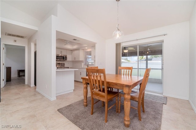 tiled dining room with vaulted ceiling and sink