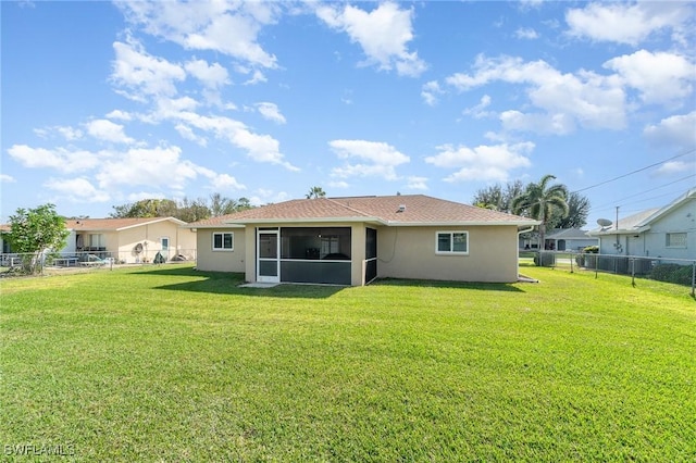 back of house with a sunroom and a lawn