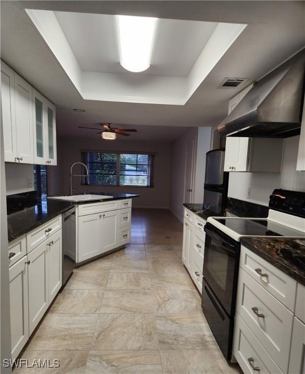 kitchen featuring electric stove, wall chimney range hood, white cabinetry, and stainless steel dishwasher