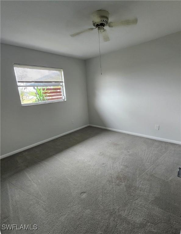 empty room with ceiling fan and dark carpet