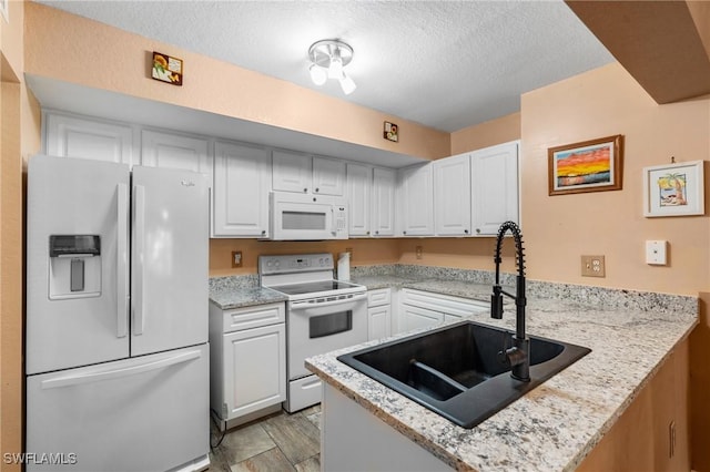 kitchen featuring sink, white cabinets, white appliances, and kitchen peninsula