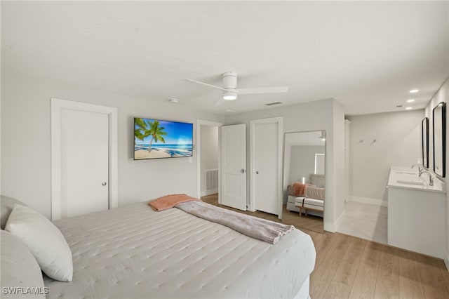 bedroom featuring ceiling fan, sink, and light hardwood / wood-style flooring