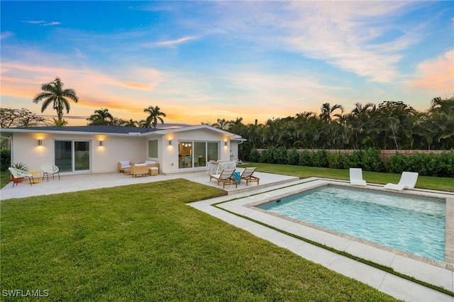 back house at dusk featuring a fenced in pool, a yard, and a patio area