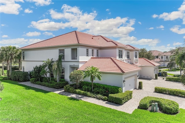 mediterranean / spanish-style house featuring decorative driveway, stucco siding, a garage, a tiled roof, and a front lawn