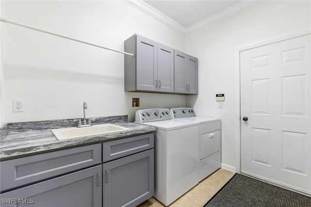 clothes washing area featuring cabinet space, crown molding, washer and dryer, and a sink
