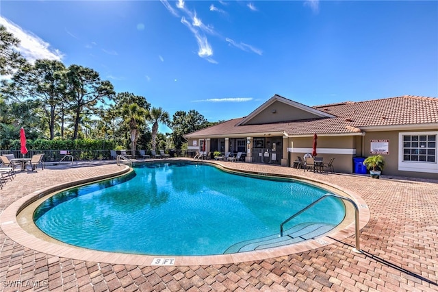 community pool with a patio and fence
