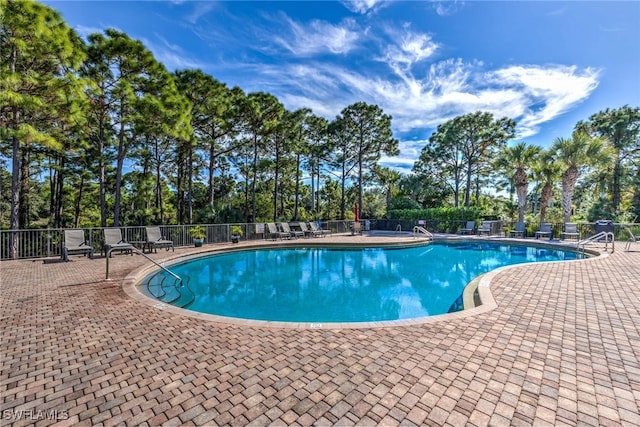 pool with a patio area and fence