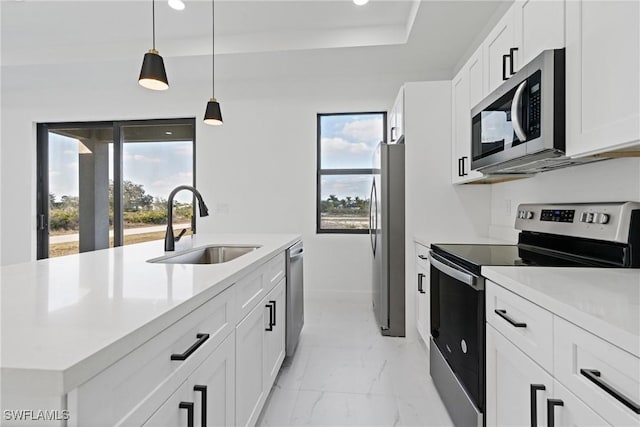 kitchen with appliances with stainless steel finishes, a wealth of natural light, decorative light fixtures, sink, and white cabinets