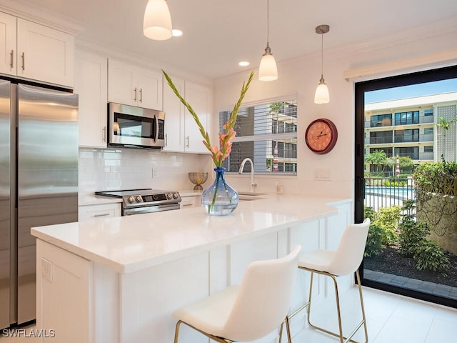 kitchen featuring stainless steel appliances, tasteful backsplash, a breakfast bar area, and white cabinets