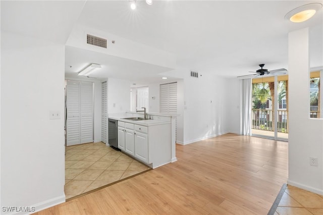 kitchen with visible vents, dishwasher, a peninsula, light wood-style floors, and a sink