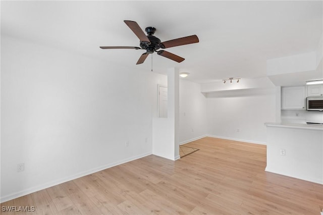 unfurnished living room featuring baseboards, ceiling fan, and light wood finished floors