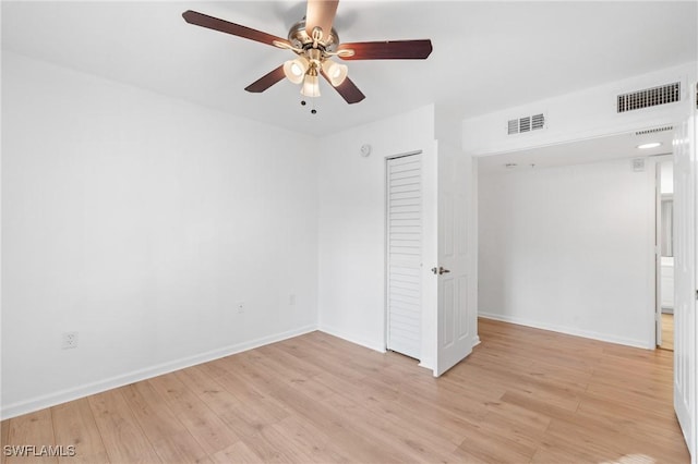 spare room featuring light wood-style floors, visible vents, and baseboards