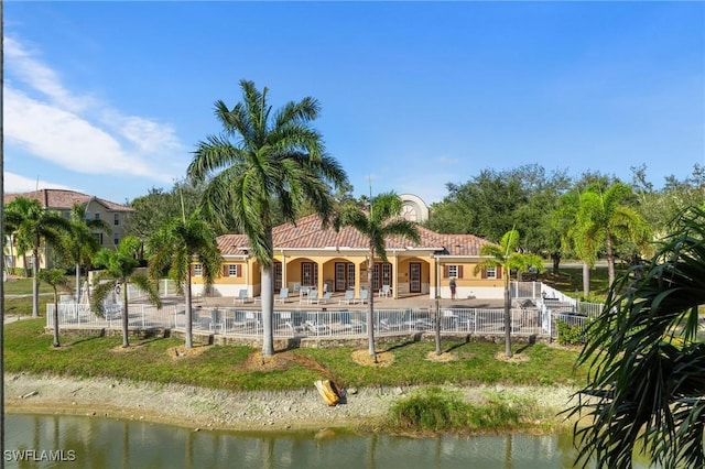 rear view of property with a water view, a community pool, a patio, and fence