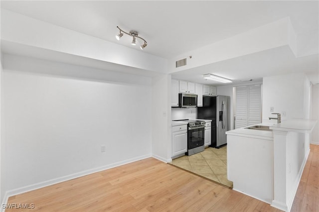 kitchen with a sink, visible vents, light wood-type flooring, and appliances with stainless steel finishes