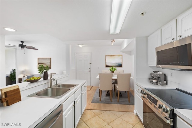 kitchen featuring light tile patterned flooring, a sink, light countertops, appliances with stainless steel finishes, and white cabinetry