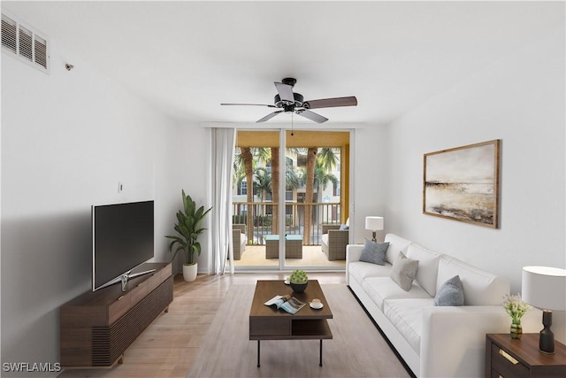 living room with visible vents, light wood-style flooring, a ceiling fan, and expansive windows