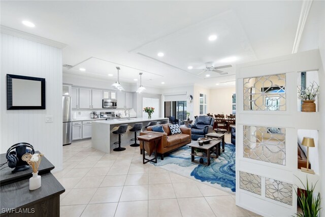 tiled living room with sink, ornamental molding, and ceiling fan