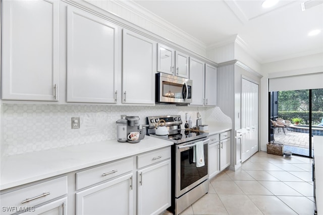 kitchen with crown molding, appliances with stainless steel finishes, light tile patterned flooring, and white cabinets