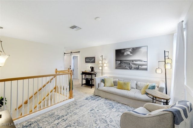 living room with a barn door and light colored carpet