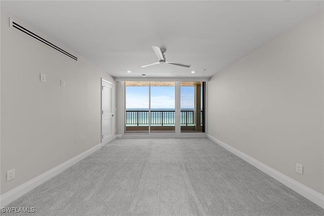 carpeted spare room featuring ceiling fan and floor to ceiling windows