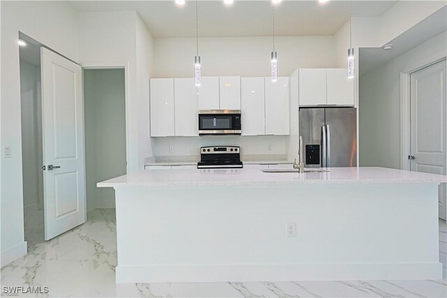 kitchen featuring decorative light fixtures, white cabinetry, sink, stainless steel appliances, and a center island with sink