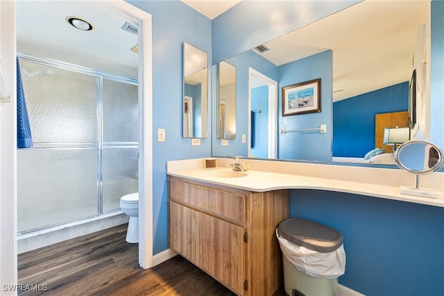 bathroom with wood-type flooring, toilet, a shower with shower door, and vanity