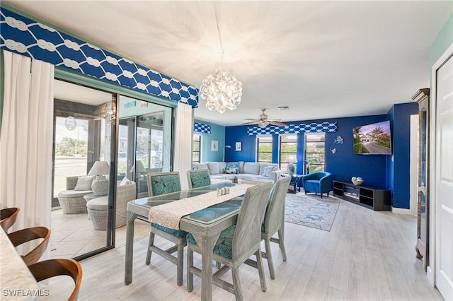 dining space with ceiling fan with notable chandelier and wood-type flooring