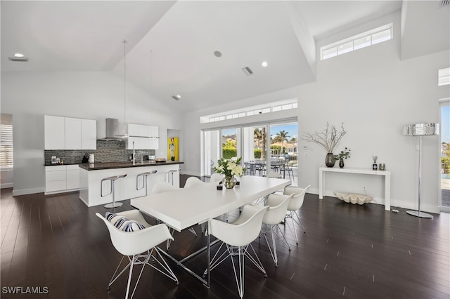 dining space featuring dark wood-type flooring and high vaulted ceiling