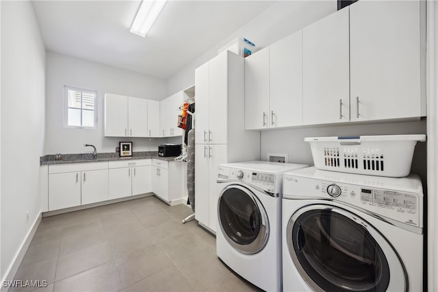 clothes washing area with sink, cabinets, light tile patterned floors, and washer and dryer