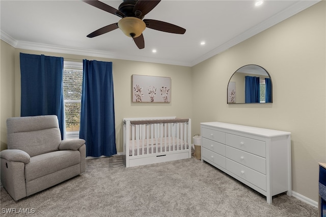 carpeted bedroom with ornamental molding, a nursery area, and ceiling fan