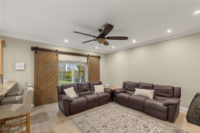 living room with light hardwood / wood-style flooring, ornamental molding, a barn door, and ceiling fan