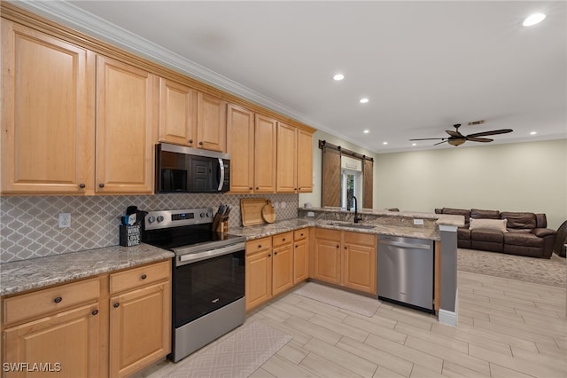 kitchen featuring stainless steel appliances, a barn door, light brown cabinetry, and sink