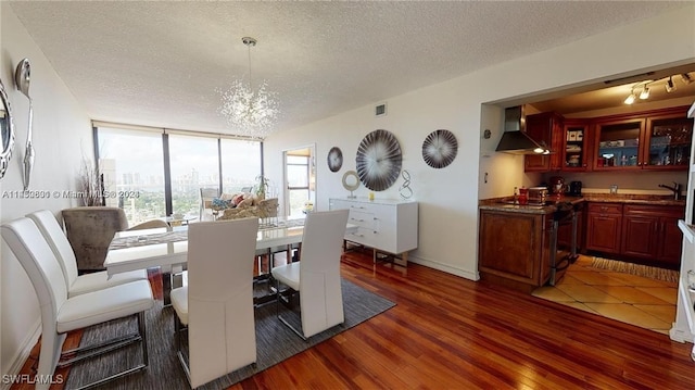 dining room featuring an inviting chandelier, expansive windows, dark hardwood / wood-style flooring, and a textured ceiling