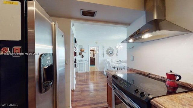 kitchen featuring stainless steel fridge, light hardwood / wood-style floors, extractor fan, and range with electric stovetop