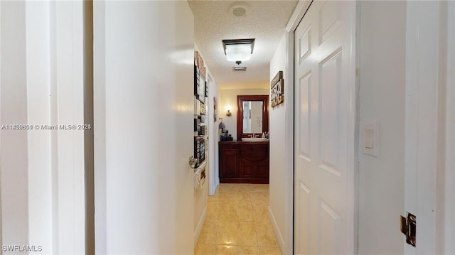 hallway with light tile patterned floors and a textured ceiling