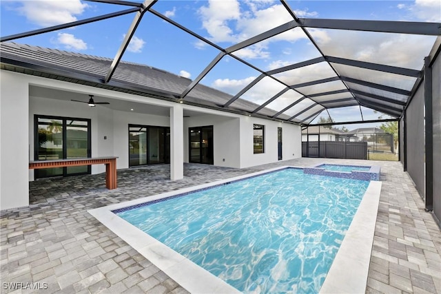 view of pool with ceiling fan, a patio area, glass enclosure, and an in ground hot tub