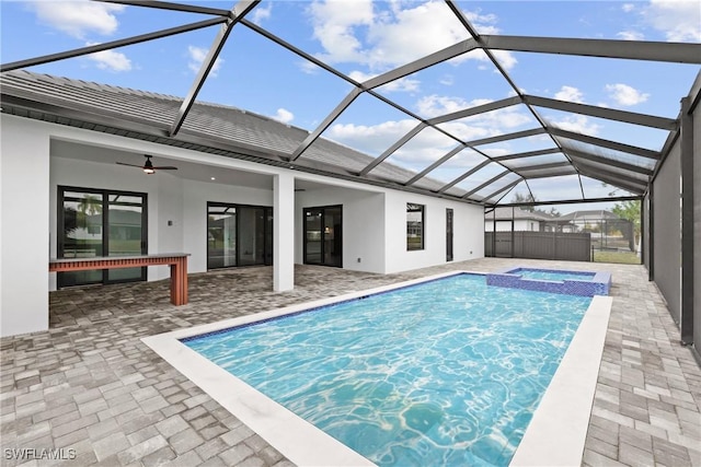 view of pool featuring a patio area, an in ground hot tub, ceiling fan, and glass enclosure