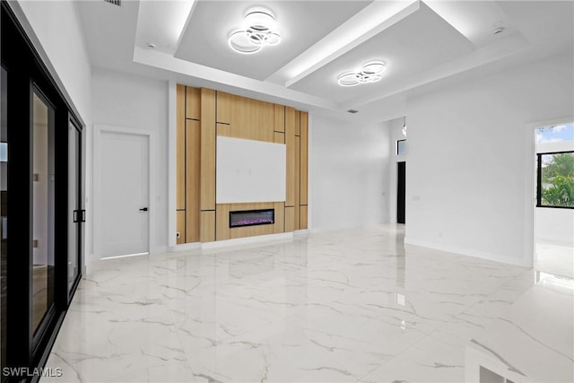 unfurnished room featuring a fireplace and a tray ceiling