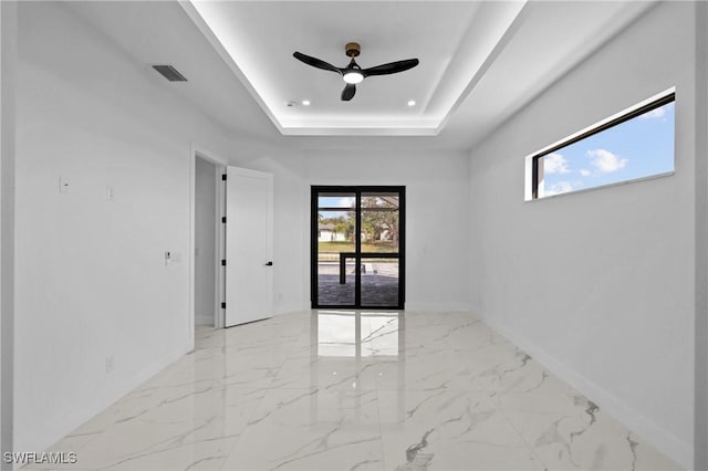 spare room featuring a raised ceiling and ceiling fan