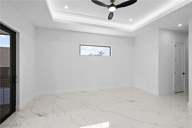 spare room with a raised ceiling, a healthy amount of sunlight, and ceiling fan