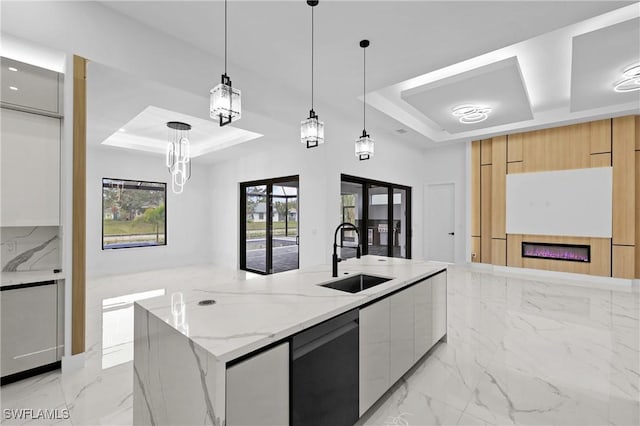 kitchen featuring light stone countertops, a raised ceiling, sink, and hanging light fixtures