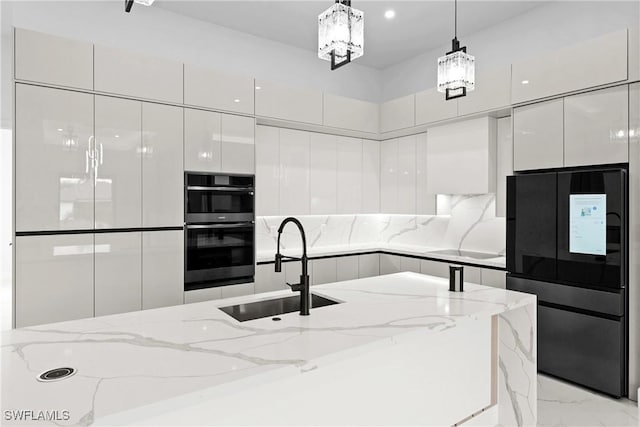 kitchen featuring sink, light stone counters, decorative light fixtures, black appliances, and white cabinets