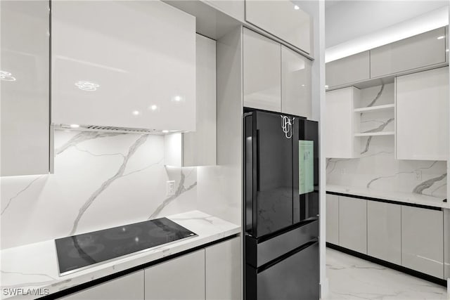 kitchen featuring white cabinetry, backsplash, light stone counters, and black appliances