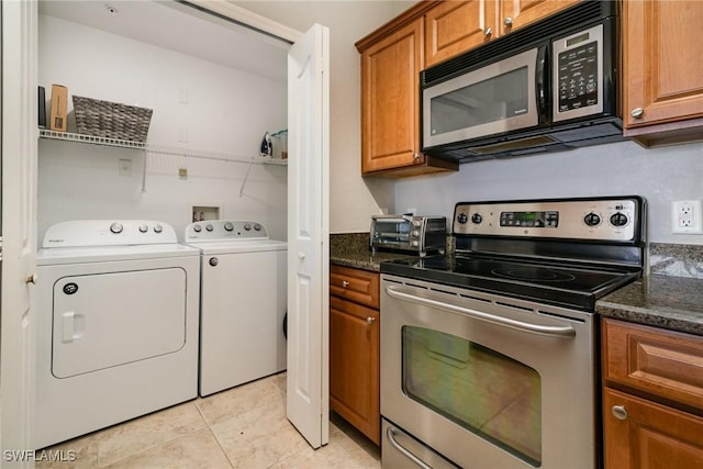 kitchen with light tile patterned floors, electric range, brown cabinets, and washing machine and dryer