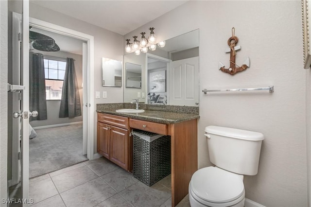 bathroom with toilet, tile patterned floors, baseboards, and vanity