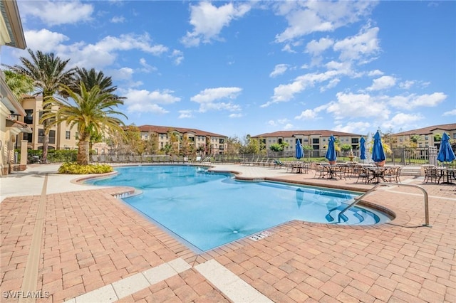 pool with a residential view, a patio area, and fence