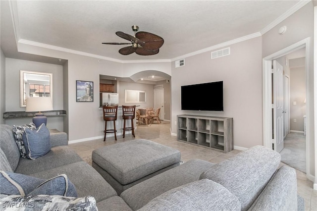 living room with baseboards, visible vents, a ceiling fan, and ornamental molding